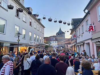 Menschenmenge auf dem Lichtenfelser Korbmarkt; Straßendekoration mit Körben, historische Architektur im Hintergrund, lebhafte Atmosphäre bei Abenddämmerung.