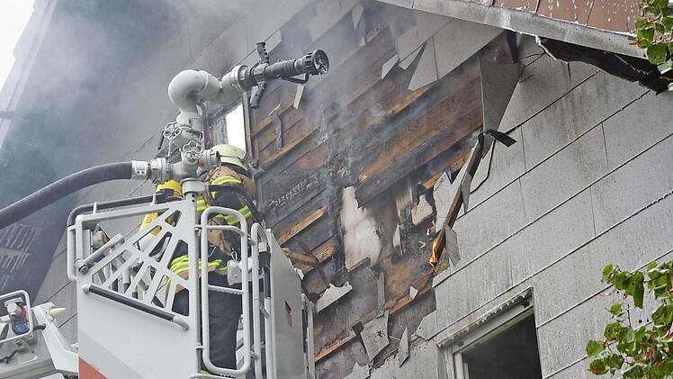 Noch zwei Stunden, nachdem die Feuerwehr den Brand unter Kontrolle hat, ist die Hitze so groß, dass Flammen aus der Fassade schlagen, als die Verkleidung abgerissen wird.