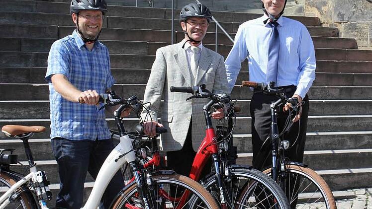 Axel Nordmann vom "Radladen" bei der Übergabe der E-Bikes an den Leiter des Bauamts, Ordinariatsrat Josef Schwab, und den Leiter der Revision, Klaus Hofmann (von links). Foto: Pressestelle Erzbistum/Christoph Gahlau
