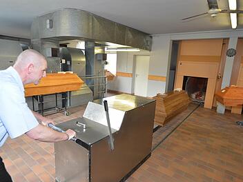 Jürgen Matl schiebt einen Sarg langsam in die Brennkammer des Ofens. Foto: Ronald Rinklef
