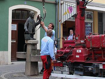 Martin Ruggaber entfernt den Transportgurt vom Gurken-Alex. Die kleine Bronzefigur steht wieder sauber und stabil an ihrem angestammten Platz. Foto: Helke Renner