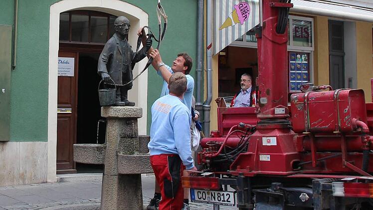 Martin Ruggaber entfernt den Transportgurt vom Gurken-Alex. Die kleine Bronzefigur steht wieder sauber und stabil an ihrem angestammten Platz. Foto: Helke Renner