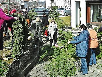W&auml;hrend Edith Hahn (links) und die "Montagsbastler" bereits flei&szlig;ig am Binden sind, liefern Mitarbeiter des Bauhofs gro&szlig;e Mengen Fichtenzweige an. Mit rund 300 bunten Eiern beh&auml;ngt, wird die Osterkrone in den kommenden Wochen den Vorplatz des Friedrich-Baur-Seniorenzentrums Sankt Kunigund schm&uuml;cken.  Foto: Bernd Kleinert
