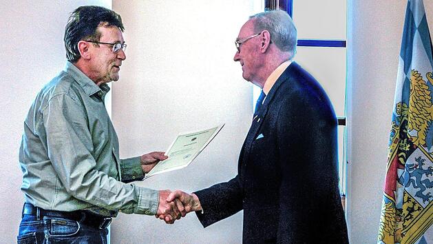 Die bayerische Fahne macht's feierlich: Josef Fuchs (links), im Landratsamt Haßberge für Einbürgerungen zuständig, übergibt die Einbürgerungsurkunde an Alan Stockbridge aus Ebern. Fotos: privat