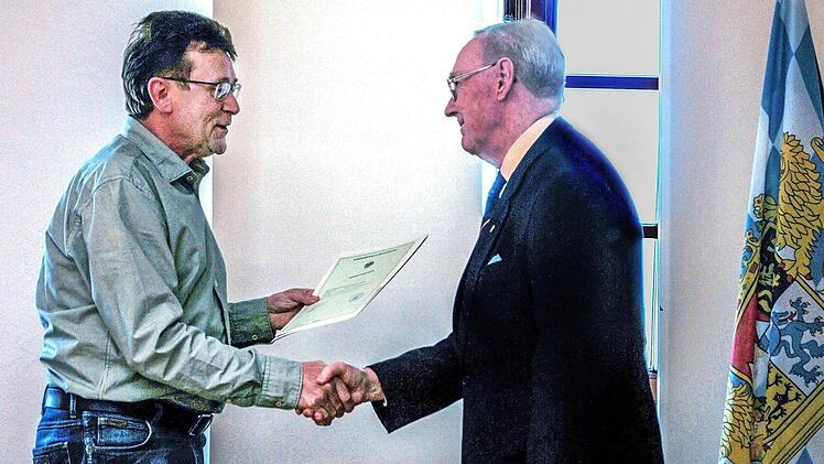 Die bayerische Fahne macht's feierlich: Josef Fuchs (links), im Landratsamt Haßberge für Einbürgerungen zuständig, übergibt die Einbürgerungsurkunde an Alan Stockbridge aus Ebern. Fotos: privat