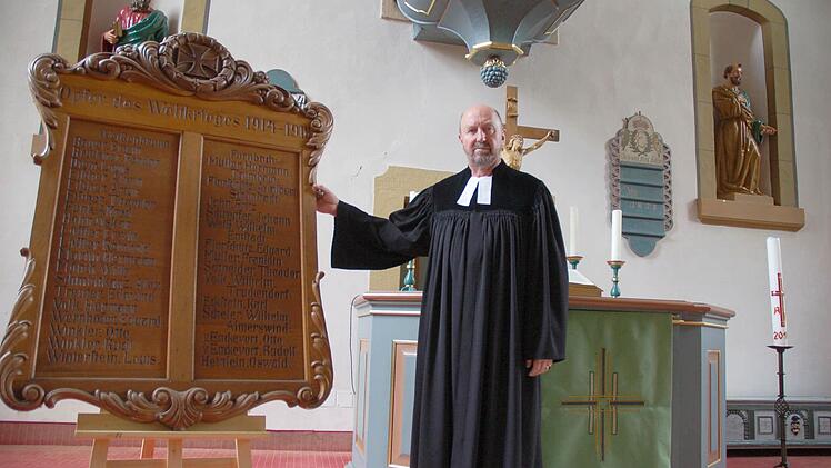 Pfarrer Arnold Kroll zeigt eine der Tafeln mit Namen von Gefallenen, die jetzt wieder gut sichtbar in der Kirche stehen. Foto: Rainer Lutz