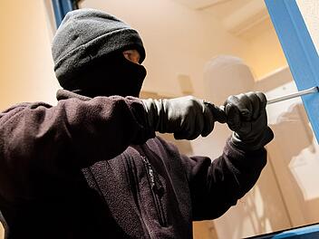 Ein als Einbrecher verkleideter Mann hebelt in der Kriminalpolizeilichen Beratungsstelle der Polizei in Hamburg ein Fenster auf. Daniel Bockwoldt, dpa