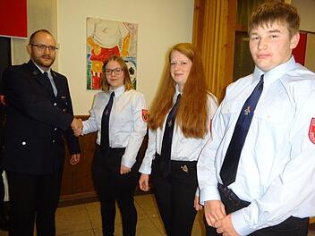 Kommandant Michael Geßner (links) nahm per Handschlag Julia Ziegler, Daniela Geßner und Steffen Geßner (von links) in den aktiven Feuerwehrdienst auf. Foto: Anton Then