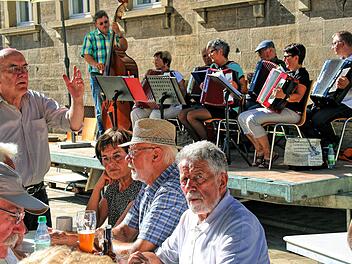 Wolfgang Blümlein, der Vorsitzende des Bürgerbad-Vereins (links), informierte die Besucher des Herbstfestes über ein Gespräch, dass er mit Ministerpräsident Markus Söder geführt hatte. Im Hintergrund die Musikschul-Akkordeongruppe, die für die Musik sorgte.  Foto: Dieter Britz
