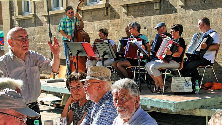 Wolfgang Blümlein, der Vorsitzende des Bürgerbad-Vereins (links), informierte die Besucher des Herbstfestes über ein Gespräch, dass er mit Ministerpräsident Markus Söder geführt hatte. Im Hintergrund die Musikschul-Akkordeongruppe, die für die Musik sorgte.  Foto: Dieter Britz