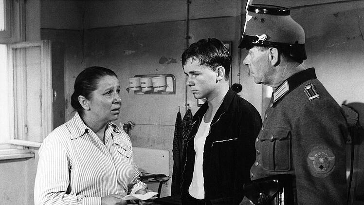 Ein Polizist liefert Sigi Bernhard (G&uuml;nther Hoffmann, Mitte) bei seiner Mutter (Edith Schultze-Westrum) ab.
