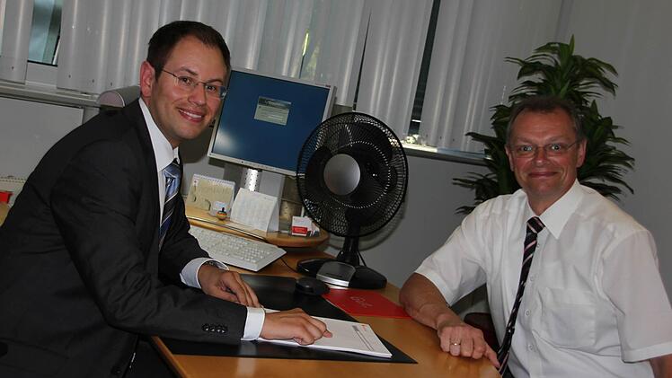 Dominic Schneider (links) und Robert Porzelt von der Sparkasse kühlen sich mit Ventilatoren ab. Foto: Sabine Herteux