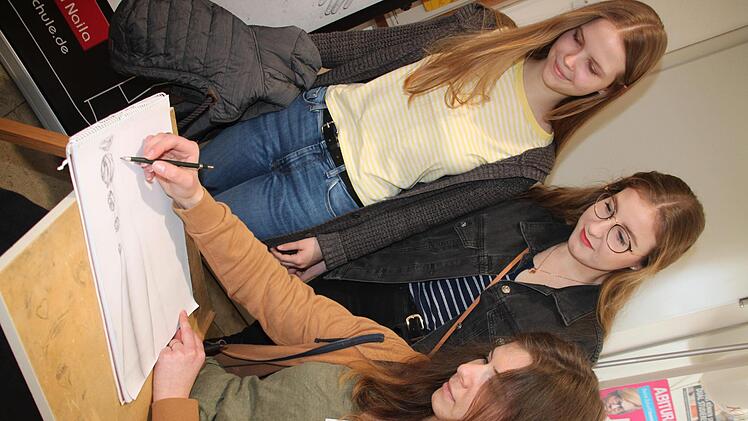 Katharina Ramming (links) und Milena  Pavlovic schauen Katharina Karen Gutt von der Bekleidungsschule Naila beim  Zeichnen zu.