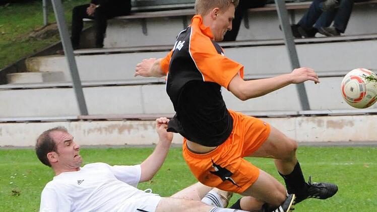 Greift auch mal zu rustikalen Mitteln: Hausens Spielertrainer Frank Dölling räumt Julian Seufert (TSV Aschach) und den Ball ab. Foto: Hopf