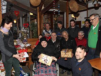Ela Reisemann (l.) überreicht ASB-Heimleiter Sebastian Beetz (vorne in der Hocke) und einigen Bewohnern die Geschenke.  Fotos: Schwind