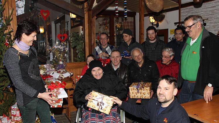 Ela Reisemann (l.) überreicht ASB-Heimleiter Sebastian Beetz (vorne in der Hocke) und einigen Bewohnern die Geschenke.  Fotos: Schwind