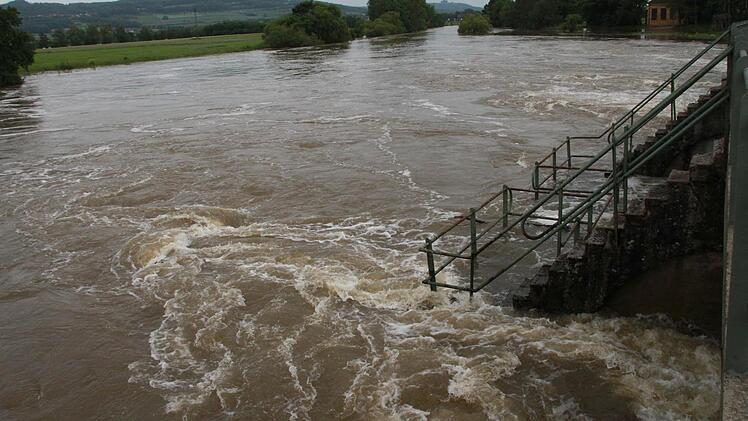 Das Wasser des Mains strömt mit unheimlicher Kraft ins Tosbecken des Kraftwerks Hausen; im Hintergrund der Staffelberg