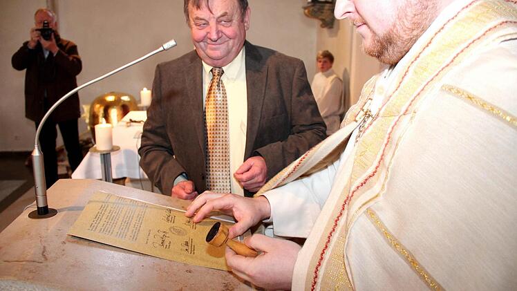 Pfarrer Ringer stempelt die unterschriebene Urkunde.