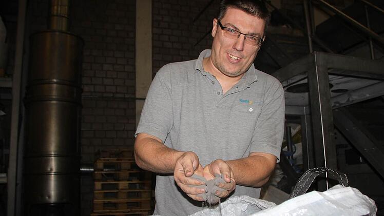 Marco Reinisch aus Bad Brückenau arbeitet seit 1996 im Metallwerk. Er zeigt, wie fein das Pulver ist, aus dem die Bauteile gepresst werden. Foto: Ulrike Müller