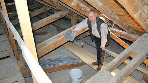 Pfarrer Armin Haas erläutert, wo die derzeitige Schieferdeckung das Regenwasser durchlässt.