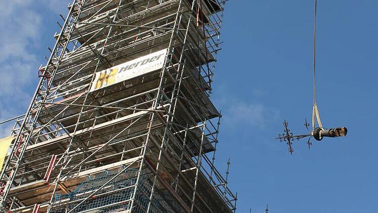 Die Spitze hängt am Kranhaken neben dem eingerüsteten Turm.