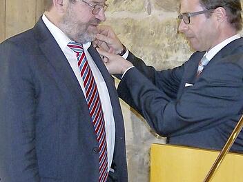 Jürgen Gros (r.) heftet dem Jubilar Wolfgang Holler die goldene Ehrennadel an.  Foto: Malbrich