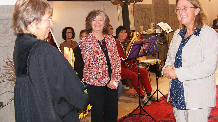 Pfarrerin Karola Schürrle (links) übergab der neuen Adelsdorfer Gemeindepädagogin Birgit Gräter (rechts) einen Weinstock und bat für sie um den Segen Gottes.