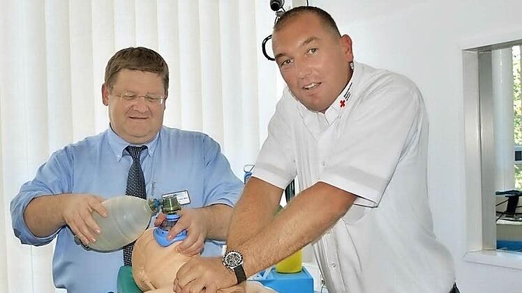 So geht das: Heiko Stäblein vom Roten Kreuz (rechts) und Dr. Michael Dinkel (links) erklären an einer Puppe, wie die Reanimation bei einem Menschen mit Herzstillstand durchgeführt wird. Wichtig ist die Herzmassage.