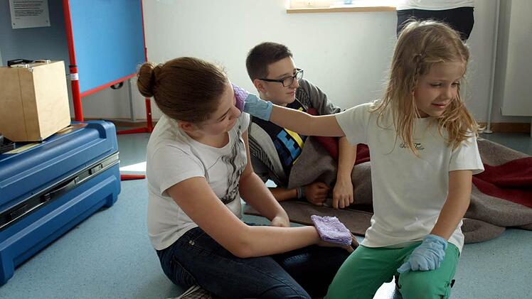 Wespenstiche muss man kühlen - Lilli Geiger von den Bambinis Schneckenlohe II macht das bei Jana Nickol ganz richtig. Im Hintergrund Luca Finazzo.