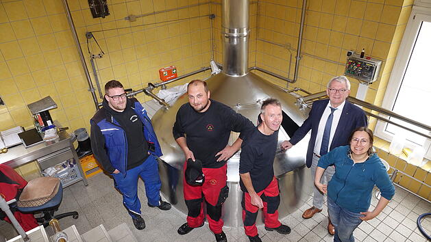 F&uuml;nf Personen stehen um eine Brauanlage in einer Brauerei mit gelben Kacheln. Sie arbeiten gemeinsam am Landkreisbier "36 Kreisla", das dieses Jahr ein naturtr&uuml;bes Exportbier ist.