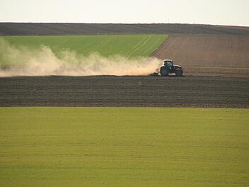 Ein Traktor auf einem Feld bei Draisdorf, aufgenommen im April, zieht eine lange Staubfahne hinter sich her. Am Obermain ist es zurzeit sehr trocken. Foto: Matthias Einwag