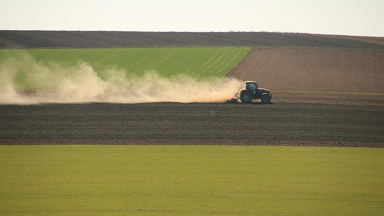 Ein Traktor auf einem Feld bei Draisdorf, aufgenommen im April, zieht eine lange Staubfahne hinter sich her. Am Obermain ist es zurzeit sehr trocken. Foto: Matthias Einwag