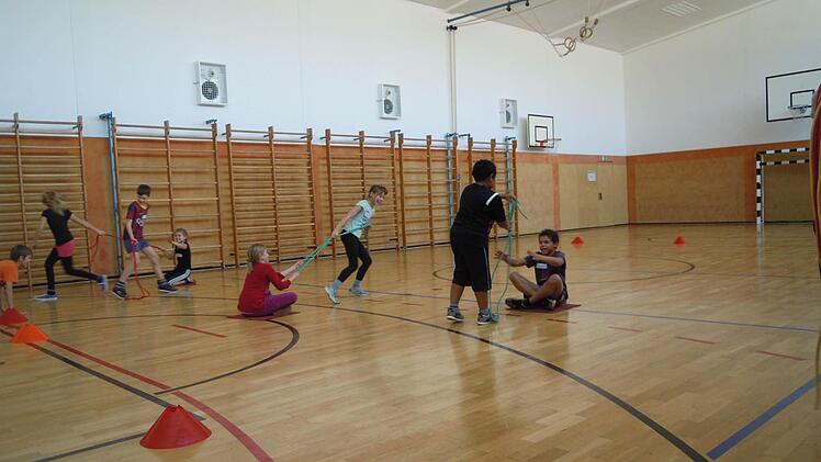 Die Grundschüler müssen sich auf Teppichen einmal durch die Turnhalle ziehen. Wer am Schnellsten ist, gewinnt. Foto: Julia Raab