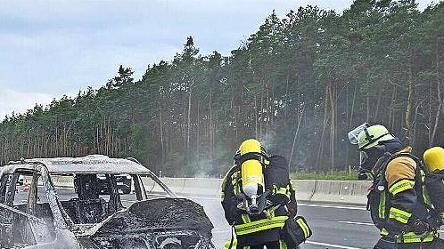 Feuerwehrleute der Freiwilligen Feuerwehr H&ouml;chstadt l&ouml;schen ein brennendes Auto auf der A3.
