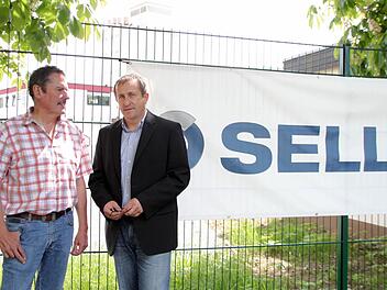 Werbeprovisorium am Zaun: Geschäftsführer Hans Sell (links) und Ralph Schramm, Spartenleiter für den Bereich Krankenhaus, vor dem neu angemieteten Gelände in der Albert-Ruckdeschel-Straße, wo künftig 25 Büroangestellte aus dem Firmenzweig Haustechnik arbeiten. Die offizielle Einweihungsfeier soll am 14. Juni steigen. Foto: Jochen Nützel