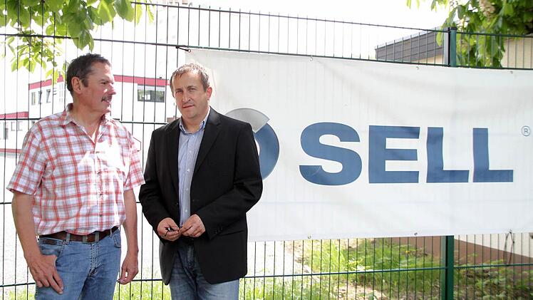 Werbeprovisorium am Zaun: Geschäftsführer Hans Sell (links) und Ralph Schramm, Spartenleiter für den Bereich Krankenhaus, vor dem neu angemieteten Gelände in der Albert-Ruckdeschel-Straße, wo künftig 25 Büroangestellte aus dem Firmenzweig Haustechnik arbeiten. Die offizielle Einweihungsfeier soll am 14. Juni steigen. Foto: Jochen Nützel