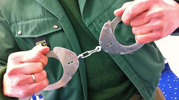 Ein Vorführbeamter zeigt die Handschellen, die er einem Angeklagten abgenommen hat - Symbolfoto aus dem Bamberger Gericht.