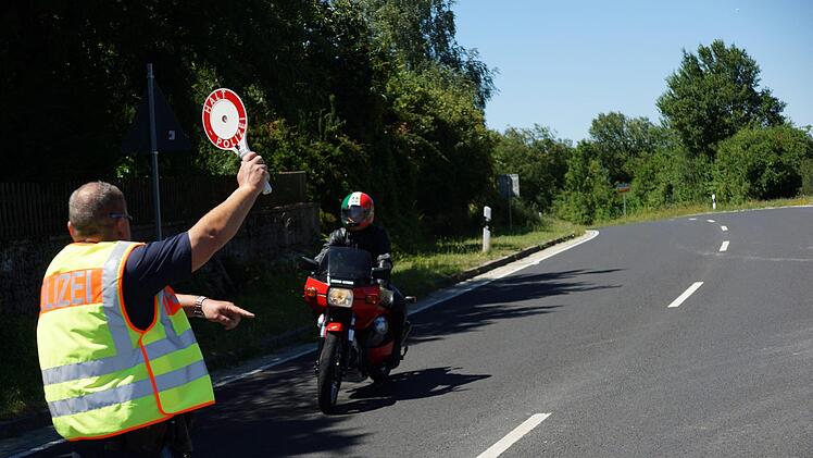 Ralf Peter winkt einen Motorradfahrer aus dem Verkehr heraus.Foto: Arkadius Guzy