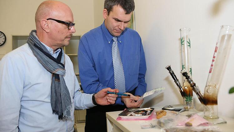Christopher Rosenbusch (rechts) und Kriminalhauptkommissar Roland Zoeke von der Polizei in Bamberg stehen an einem Tisch mit in der Region beschlagnahmten Drogen-Utensilien. Foto: Matthias Hoch
