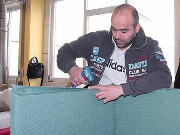 Abolfazl Tajik tackert den Bezug einer Akustikkabine fest. Foto: Simone Bastian