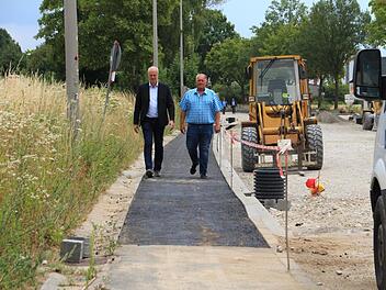 Bürgermeister Brehm (links) und Freibadchef Philipp testen den vorab freigegebenen Fußweg entlang der Baustelle. Foto: Andreas Dorsch