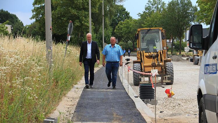 Bürgermeister Brehm (links) und Freibadchef Philipp testen den vorab freigegebenen Fußweg entlang der Baustelle. Foto: Andreas Dorsch