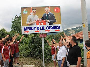 Das Plakat im türkischen Devrek zeigt Özil mit Erdogan bei einem Termin in London. Die Pfeile unter dem Plakat deuten in Richtung der "Mesut-Özil-Straße". Die Straße wurde 2012 nach dem Arsenal-Profi benannt. Foto: Muharrem Terzi/dpa