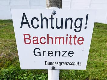 Vor einem kleinen Bach ist in Mödlareuth ein Schild mit der Aufschrift "Achtung! Bachmitte - Grenze. Bundesgrenzschutz" zu sehen. Als vor 25 Jahren die Deutsche Einheit besiegelt wurde, hegte das bayerisch-thüringische Grenzland große Hoffnungen. Foto: Nicolas Armer/dpa