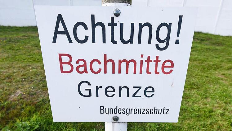 Vor einem kleinen Bach ist in Mödlareuth ein Schild mit der Aufschrift "Achtung! Bachmitte - Grenze. Bundesgrenzschutz" zu sehen. Als vor 25 Jahren die Deutsche Einheit besiegelt wurde, hegte das bayerisch-thüringische Grenzland große Hoffnungen. Foto: Nicolas Armer/dpa