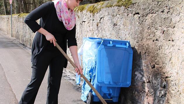 Anna Holzheimer versucht, die geschmolzenen Reste der Mülltonne zu entfernen.  Foto: Thomas Malz