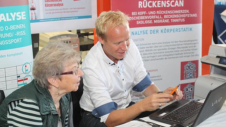 Marc Bögelein bespricht mit einer Messebesucherin das Ergebnis der Laufbandanalyse.