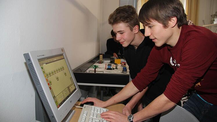 Gabriel Moser und Thomas Henning (hinten) versuchen dem Roboter das einzuhauchen, was er machen soll. Das Programming erfolgt über ein spezielles Baukastensystem.