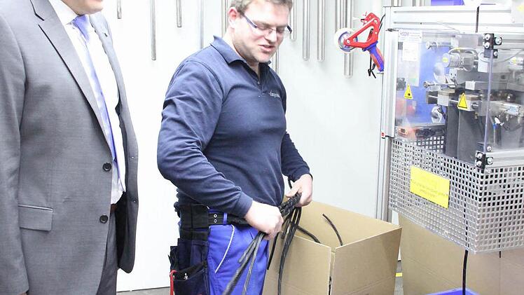 Tommy Alig an einer Maschine, die Geflechtschläuche schneidet. Links Geschäftsführer Matthias Littig.  Foto: Friedwald Schedel