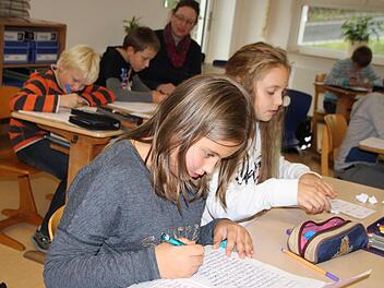 Hausaufgabenbetreuung am Nachmittag: Franziska (von links) und Justine beschäftigen sich still, während im Hintergrund Lehrerin Petra Fabinger Robin und Nikita beim Schreiben hilft. Foto: Ulrike Müller